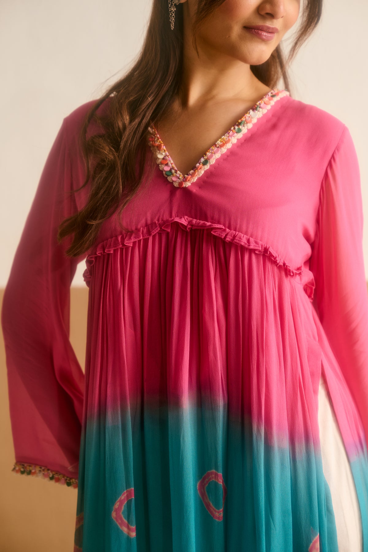 Woman wearing a pink and teal kurta with intricate details.