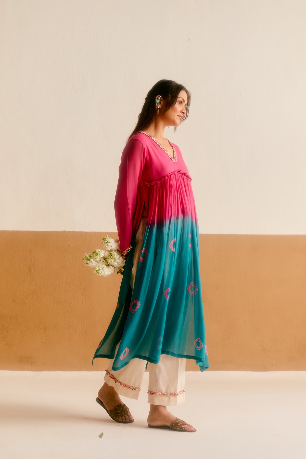 Woman wearing a pink and blue ombre hand tied and dyed kurta with khar cotton pants. 