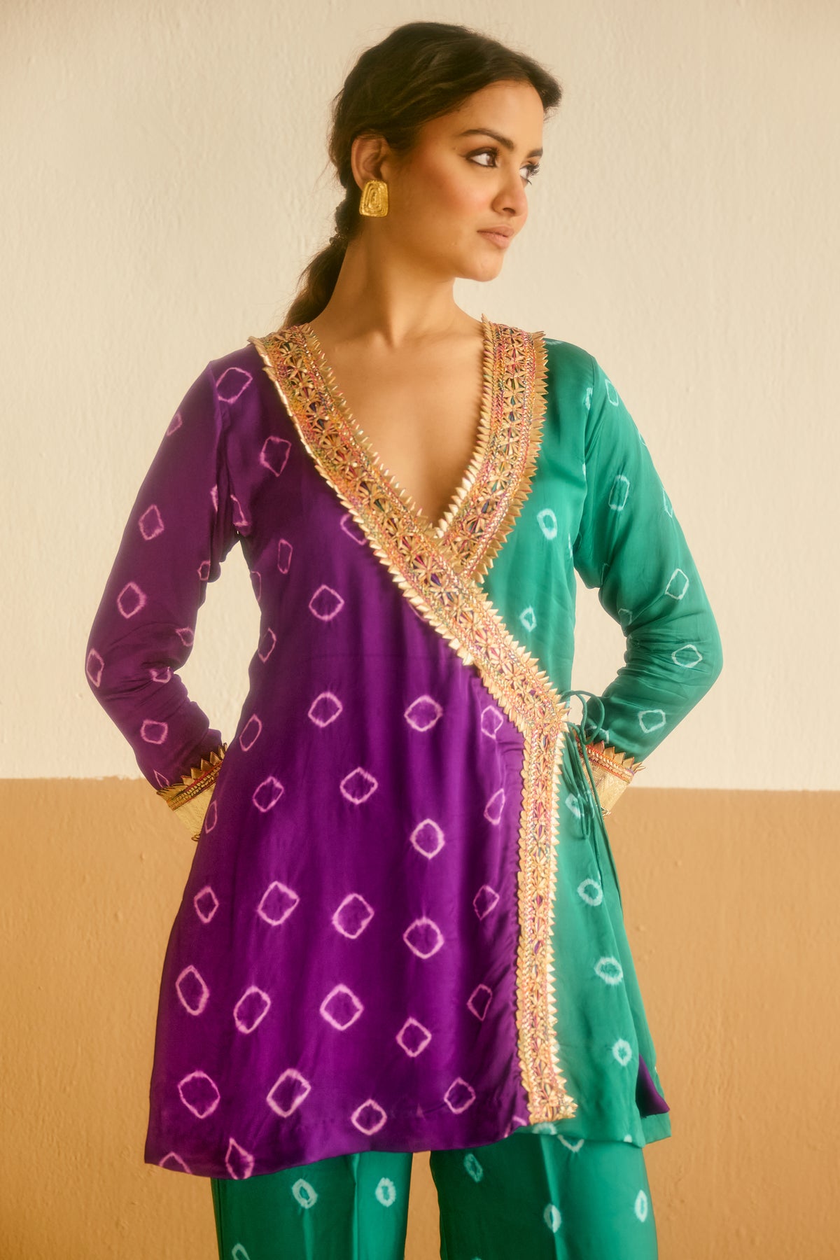 Woman wearing a purple and green tied and dyed bandhani outfit with intricate patterns.